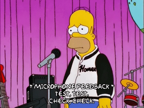 Homer Simpson taps on a microphone. The caption reads, *Microphone feedback* "Test, test. Check, check."